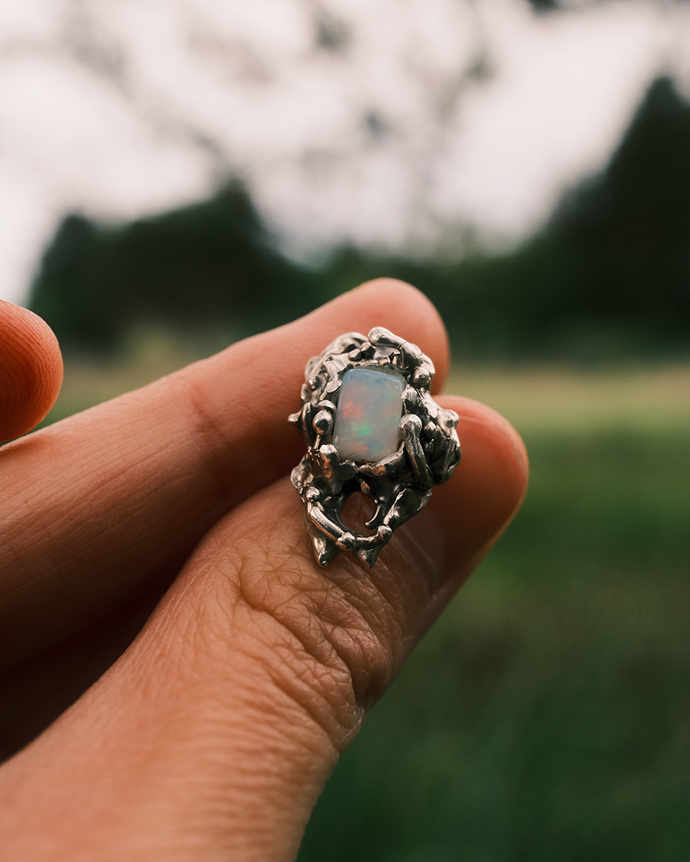 Détail boucle d’oreille artisanale en argent avec opale éthiopienne en extérieur