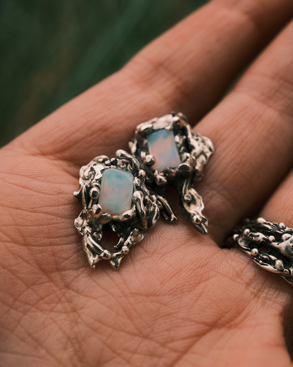 Paire de boucles d’oreilles artisanales en argent et opales dans une main gros plan