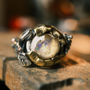 Bague artisanale Lueur Antique Artefact n°30 en argent 925 et laiton, ornée d'une opale mexicaine aux reflets verts et violets, vue de face.